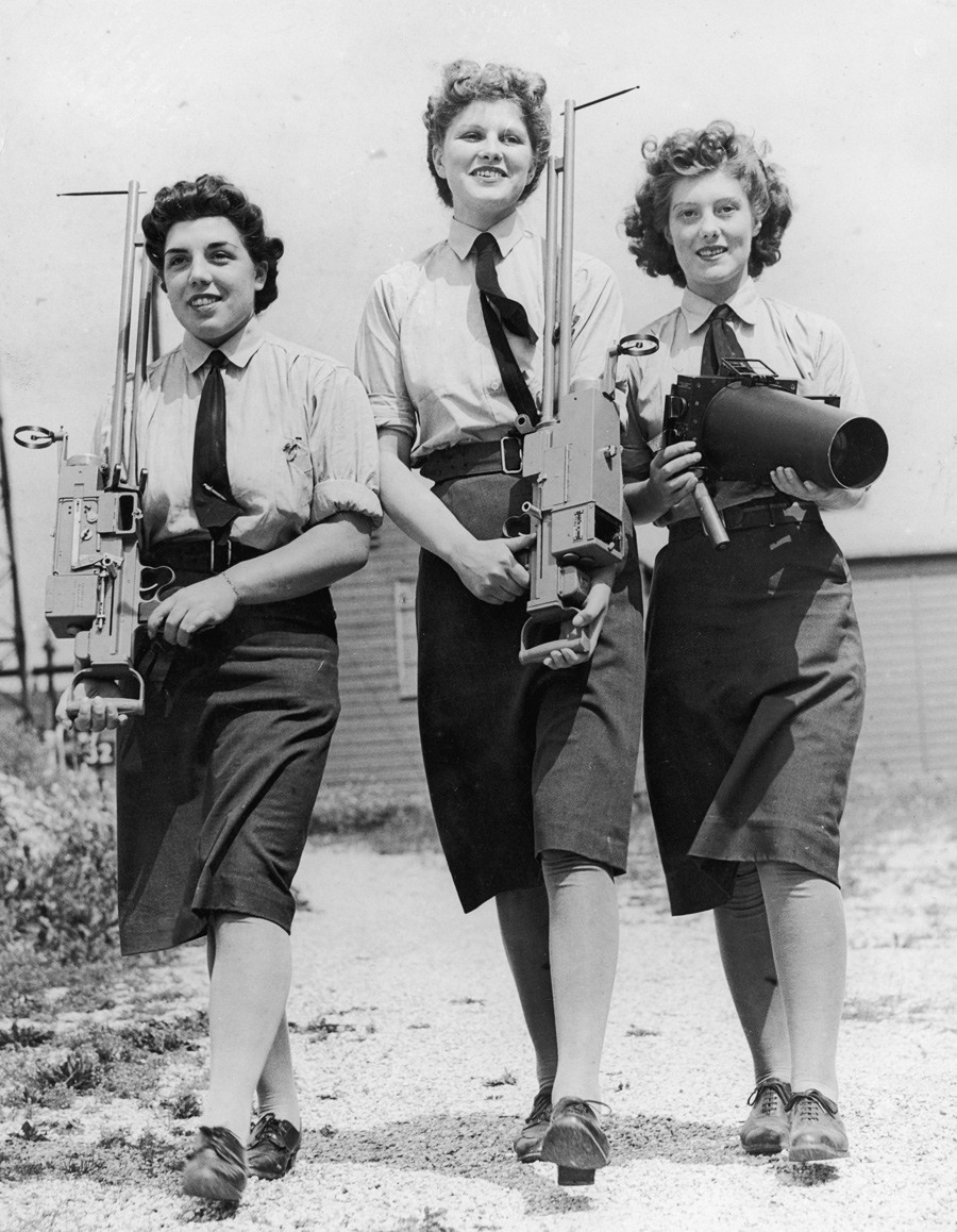 نرى في هذه الصورة ثلاثة نساء ينتمين للقوات الجوية للخدمة الإقليمية المساعدة النسائية، وهن مجهزات بآلات كاميرا أرضية وجوية من أجل أعمال تفحص وصيانة، حوالي سنة 1943.