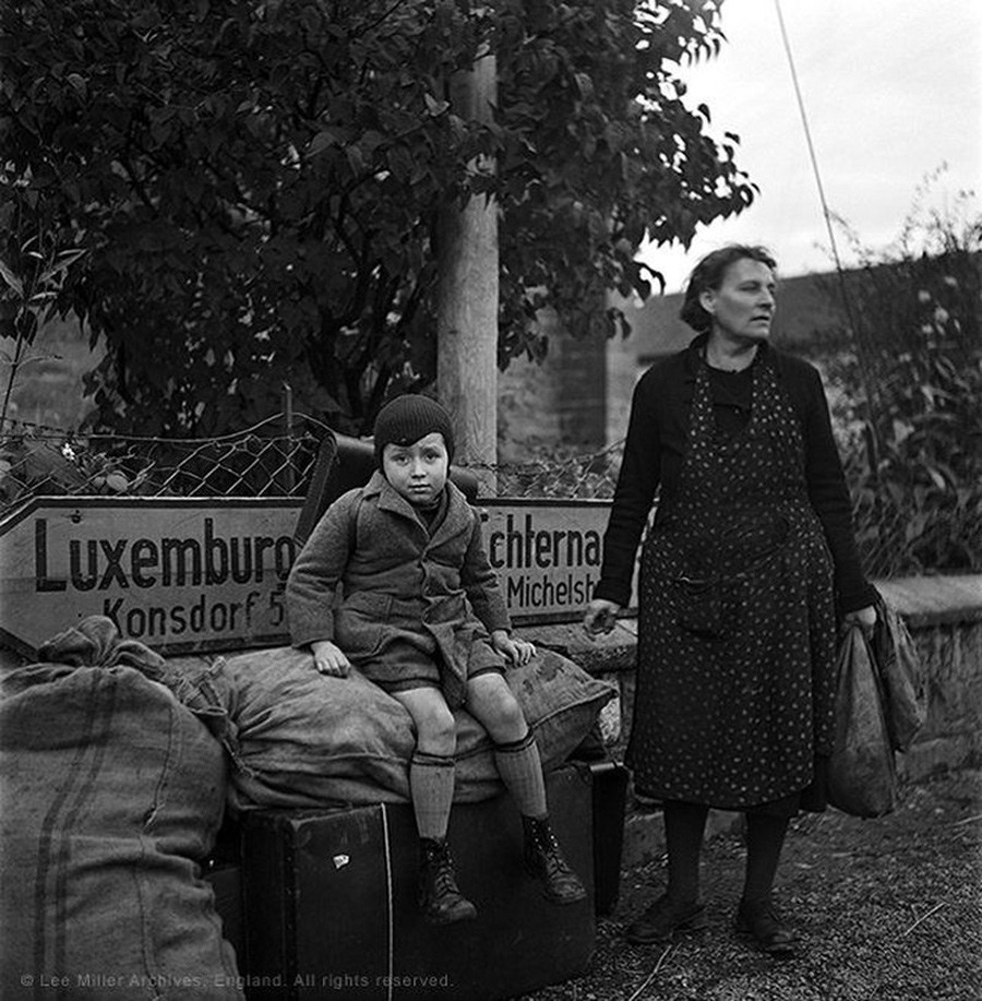 امرأة وابنها المتعبان والمنهكان يقبعان منتظرين في مفترق الطرق من أجل وسيلة نقل تقلهما في (لوكسمبورغ) في سنة 1945.
