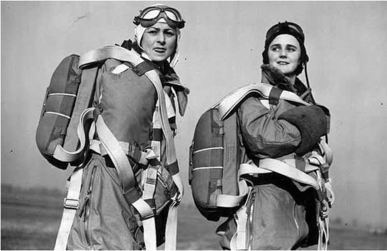 على اليسار نرى الطيارة (مونا فريدلاندر)، وعلى اليمين الطيارة (جوان هيوز) وهما ترتديان المظلات من أجل تحليق استعراضي لدى خدمة النقل الجوي للمساعدة الإقليمية النسائية: