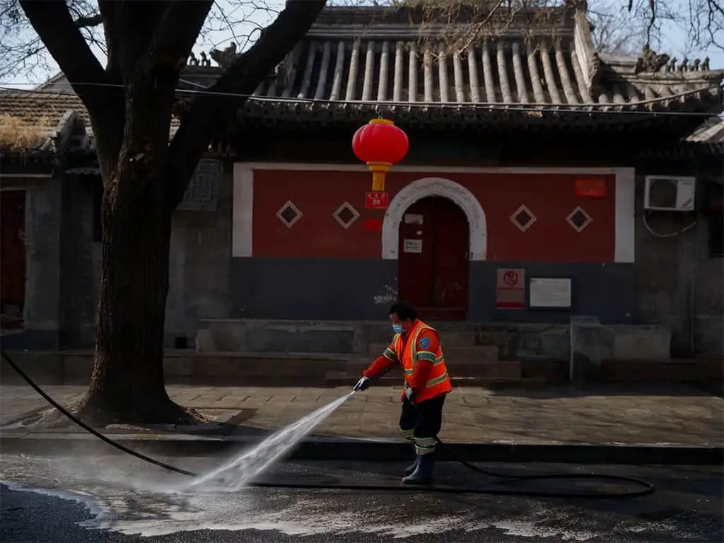 عامل يرش الشارع بمطهر في بيكين بالصين.