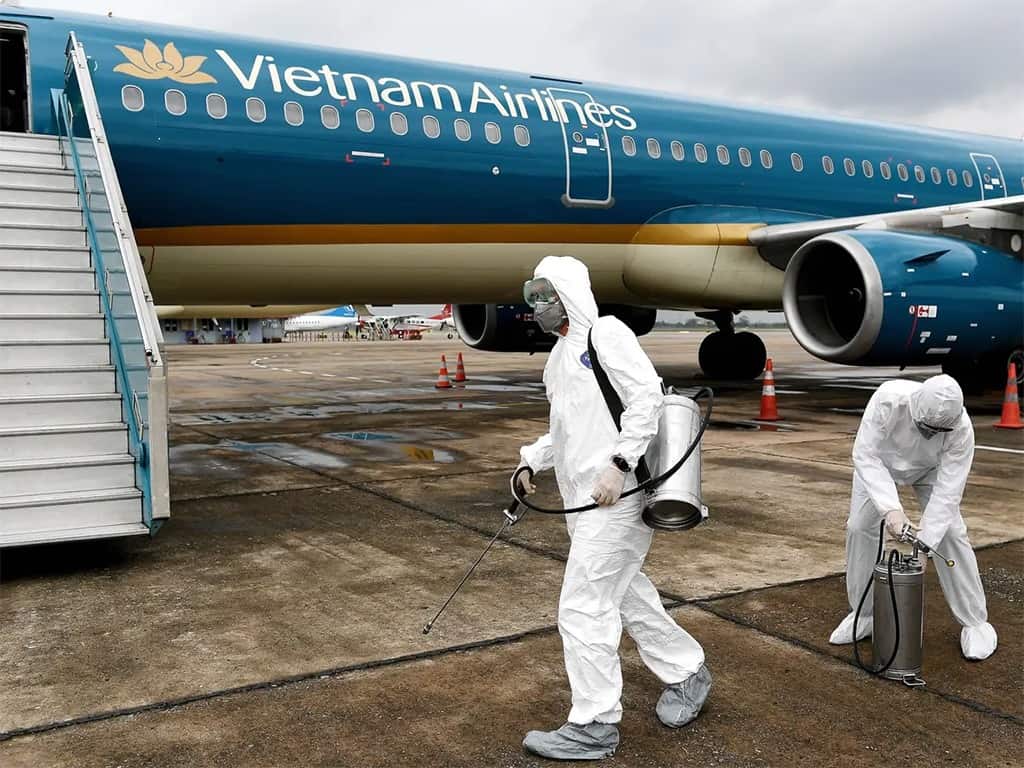 موظفون يرتدون بذلات واقية بينما يتحضرون لرش المطهرات من أجل تعقيم طائرة تابعة للخطوط الجوية الفيتنامية في خضم مخاوف من انتشار وتفشي مرض (كوفيد-19) الذي يسببه فيروس كورونا الجديد.