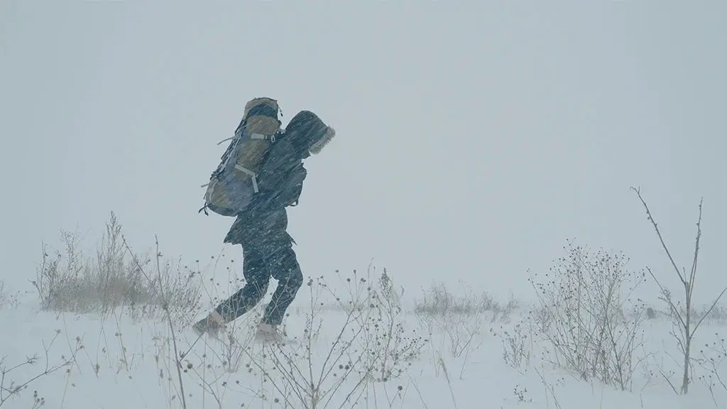 رجل يسير وسط العاصفة الثلجية.